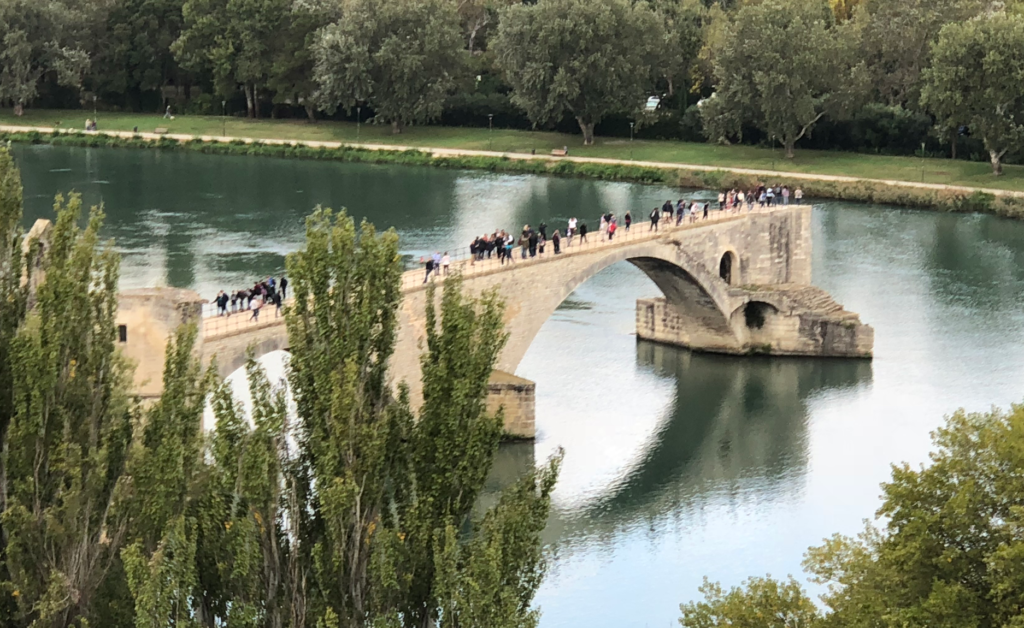 Avignon's medieval bridge with travelers on it (Pont Saint-Bénézet)